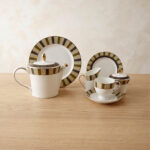 A complete 24-piece luxury porcelain tea set featuring a modern olive green and black striped pattern with gold accents, displayed on a wooden surface