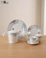 A complete 24-piece luxury porcelain tea set featuring a delicate blue floral pattern on white china with silver rims, displayed on a wooden table.