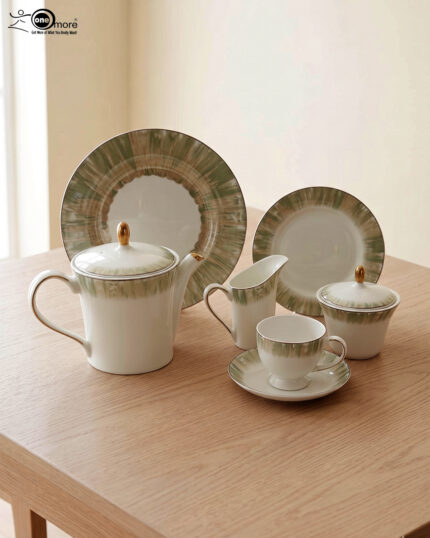 A 24-piece luxury porcelain tea set featuring white ceramic with a soft green brushstroke border and gold-tone accents, arranged on a light wooden table.