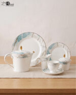 A 24-piece luxury porcelain tea set featuring a white base, marble-patterned rims in blue and grey, and delicate gold detailing, arranged on a wooden table.