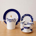 A 24-piece luxury tea set featuring white porcelain with deep blue floral patterns and gold-rimmed accents, including a teapot, cups, saucers, and plates.