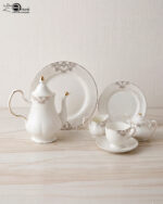 A luxurious 24-piece white porcelain tea set featuring delicate gold filigree patterns, including a teapot, teacups, saucers, plates, and serving pieces displayed on a marble-textured surface
