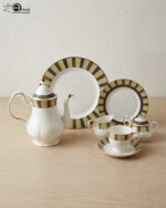 : A complete 24-piece porcelain tea and dining set featuring white ceramic with gold and olive-green striped rims, including plates, cups, saucers, a teapot, a sugar bowl, and a milk creamer arranged on a wooden surface.