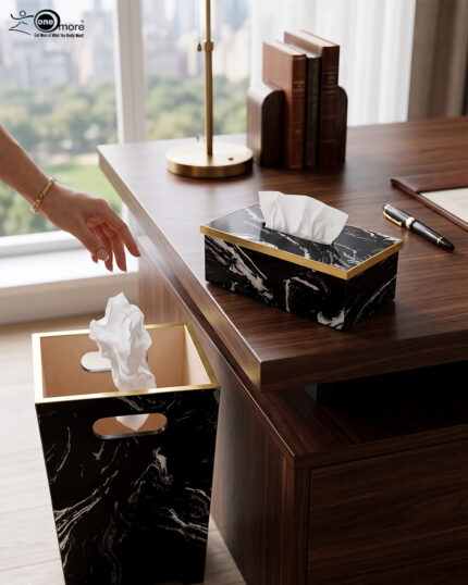 A matching executive desk accessory set featuring a black marble pattern wastebasket and a rectangular tissue box cover with elegant gold trim, placed on a dark wooden office desk.