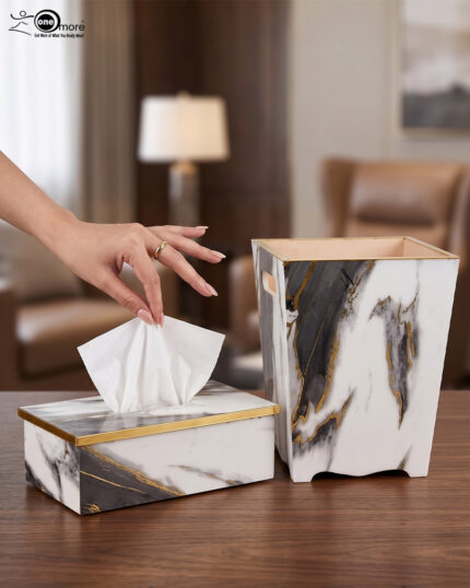 A luxury white and black marble-patterned tissue box holder and matching wastebasket with elegant gold trim, displayed on a wooden table.