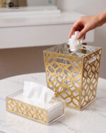 Clear acrylic dustbin and matching tissue box holder with a gold geometric lattice pattern on a white marble tabletop.