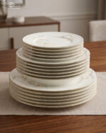 A stacked 18-piece super bone china plate set from Onemore Crockery featuring floral patterns and gold rims, displayed on a wooden table.