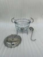 Paramount Series 4-liter glass food warmer with a stainless steel stand, lid, and ladle, featuring a buffet burner holder on a wooden dining table.