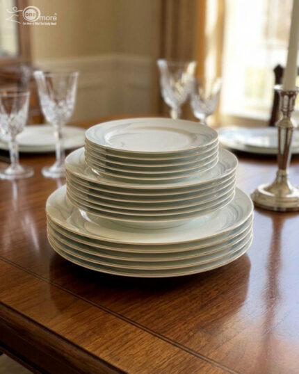 A stacked 18-piece white super bone china plate set on a wooden dining table, featuring 6 rice plates, 6 deep plates, and 6 quarter plates with a subtle design