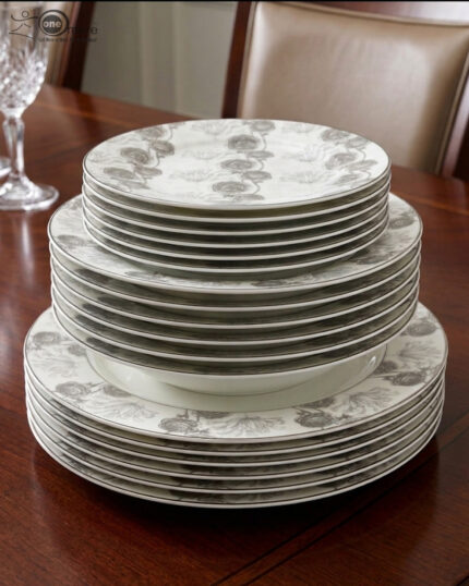 Stacked 18-piece super bone china plate set with grey floral patterns, including rice plates, deep plates, and quarter plates on a wooden dining table.