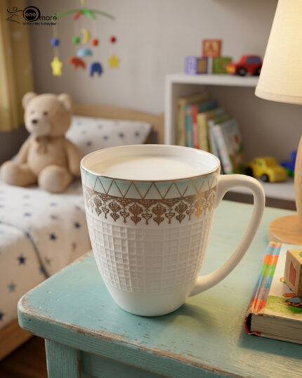 A high-angle close-up of a white bone china mug filled with milk, featuring a gold filigree border and textured lattice design, resting on a rustic blue wooden table in a brightly lit room