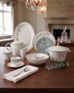 A luxury 61-piece Super Bone China dinner set with blue floral patterns and silver rims displayed on a wooden dining table, including plates, bowls, a teapot, and a serving casserole.