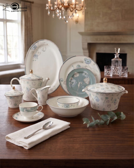 A luxury 61-piece Super Bone China dinner set with blue floral patterns and silver rims displayed on a wooden dining table, including plates, bowls, a teapot, and a serving casserole.