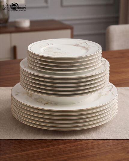 A complete super bone china dinnerware set in 7.jpg, featuring white plates, bowls, a teapot, and tea cups adorned with delicate cream floral patterns and luxurious gold-rimmed edges on a wooden surface.