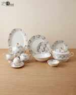 A complete white Super Bone dinner set featuring grey floral patterns and gold accents, including plates, bowls, a teapot, and serving dishes, displayed on a wooden surface in 3.jpg.
