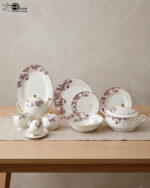 A luxury super bone china dinnerware set featuring a white base with intricate purple leaf patterns and gold accents, displayed on a wooden table