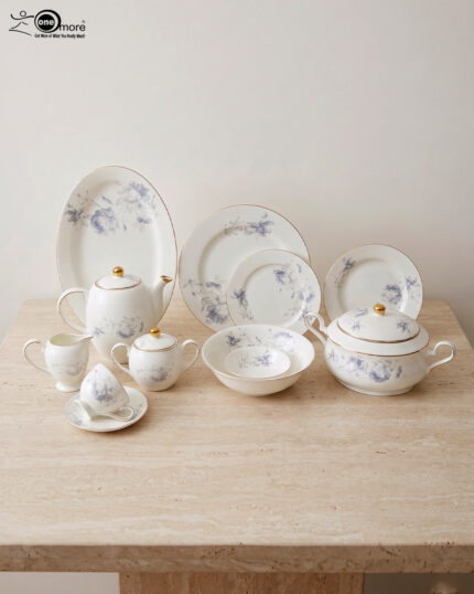 A complete super bone china dinner set in file 3.jpg featuring a delicate blue rose pattern, gold-rimmed edges, and including a teapot, plates, bowls, and serving dishes on a marble surface.
