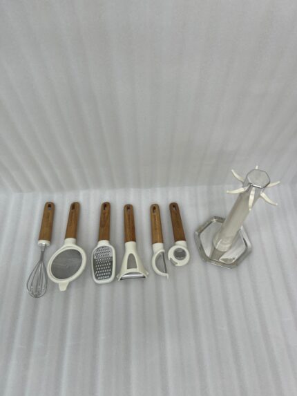 A 7-piece kitchen gadget set featuring cream-colored heads and ergonomic wooden handles, displayed both individually and hanging on a matching rotating stand on a marble countertop.