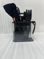 A comprehensive 17-piece kitchen tool set featuring black and rose gold silicone utensils, a matching knife set with marble-patterned handles, a vegetable peeler, kitchen shears, and a black cutting board, all stored in a clear geometric textured organizer.