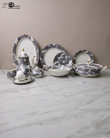 A luxury grey and white floral pattern bone china tea set and plates arranged on a wooden table, including a teapot, teacup with saucer, creamer, sugar bowl, and dinner plates.