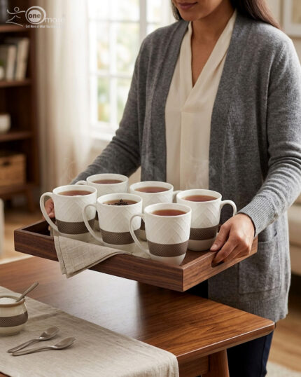 A set of six premium white ceramic tea mugs with a textured lattice design and a brown patterned base, filled with steaming tea and placed on a wooden outdoor table next to a silver spoon
