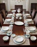 A complete super bone china dinner set featuring delicate blue and grey floral patterns with silver rims, arranged on a wooden table.