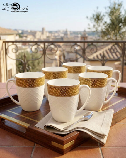 A set of elegant white bone china mugs with an embossed diamond pattern and a golden basket-weave rim, filled with steaming hot tea on a wooden table.