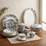 61-piece luxury Super Bone China dinnerware set with grey floral patterns and gold accents, including plates, tea pot, and serving bowls on a wooden table