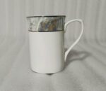 A 6-piece set of white bone china mugs as shown in 3.jpg, featuring a grey marble pattern near the rim and gold trim, displayed on a wooden desk next to books and gold spoons.