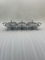 Paramount Series 3-in-1 stainless steel food warmer with three 1.5L glass dishes and buffet burners set on a formal wooden dining table.