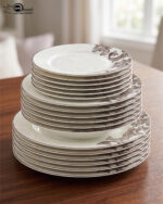 A luxury super bone china dinner set featuring a white base and intricate brown acanthus leaf patterns, including plates, bowls, a teapot, and serving dishes on a wooden table.