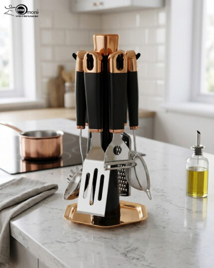 A 7-piece kitchen gadget set featuring black matte handles and rose gold accents, displayed on a matching rotating stand atop a white marble kitchen counter.