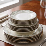 Stacked 18-piece super bone china plate set with elegant green floral patterns and gold rims on a wooden dining table setting.