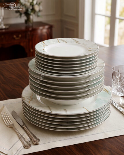 A neatly stacked 18-piece super bone china dinner plate set featuring a white and mint green marble pattern with gold veining, arranged on a dining table with silverware and a crystal glass.