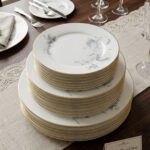 A set of 18 super bone china plates with blue floral patterns and gold rims, arranged in six place settings on a dark wooden dining table.