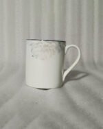 A 6-piece set of white bone china mugs as shown in 3.jpg, featuring a grey marble pattern near the rim and gold trim, displayed on a wooden desk next to books and gold spoons.