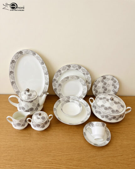 A complete Super Bone China dinner set from 6.jpg, featuring a white base with intricate grey floral borders. The set includes plates, bowls, a teapot, a tureen, and teacups displayed on a wooden surface