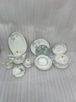 A luxury super bone china dinner set with delicate blue floral patterns and gold accents, including plates, bowls, and a tea service set on a marble surface.