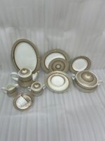 A luxury super bone china dinner set featuring a white base with gold-toned textured borders and metallic accents, displayed on a wooden table in 7.jpg.