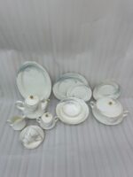 A comprehensive white super bone china dinner set from 7.jpg featuring an elegant blue leaf design and gold-rimmed edges, arranged on a wooden table. Includes plates, bowls, a teapot, cups, and a tureen.