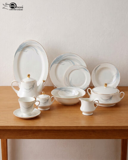 A comprehensive white super bone china dinner set from 7.jpg featuring an elegant blue leaf design and gold-rimmed edges, arranged on a wooden table. Includes plates, bowls, a teapot, cups, and a tureen.