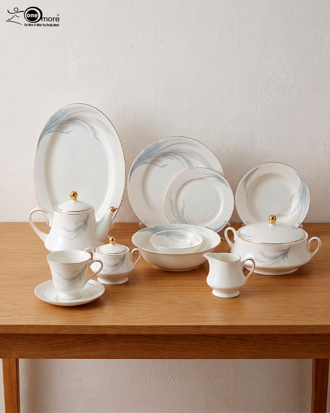 7 A comprehensive white super bone china dinner set from 7.jpg featuring an elegant blue leaf design and gold-rimmed edges, arranged on a wooden table. Includes plates, bowls, a teapot, cups, and a tureen.