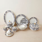 A luxurious super bone china dinner set from Onemore Crockery featuring a grey floral design and gold accents, including plates, bowls, a teapot, and serving dishes arranged on a wooden surface as seen in 7.jpg.