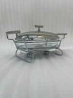 Two Paramount Series stainless steel oval food warmers in 2.4L and 3L sizes on a table runner, featuring glass bowls and polished metal lids.