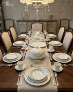 A comprehensive white super bone china dinner set from 7.jpg featuring an elegant blue leaf design and gold-rimmed edges, arranged on a wooden table. Includes plates, bowls, a teapot, cups, and a tureen.