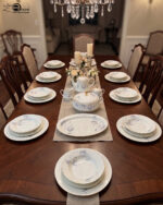 An elegant collection of super bone china dinnerware from the file 7.jpg, featuring a delicate blue rose pattern and gold-rimmed edges. The set includes a large oval platter, various sized plates, a lidded tureen, a teapot, a creamer, a sugar bowl, and a teacup with a saucer, all arranged on a light marble surface against a neutral background.