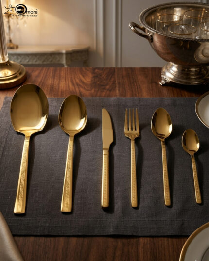 Luxury 36-piece gold-finished cutlery set featuring a geometric Greek key handle design, displayed elegantly on a dark grey placemat.