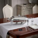 One More 3-liter premium stainless steel rectangular chafing dish with ornate legs and dual buffet burners on a luxury dining table setup.