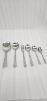 Overhead view of a 37-piece stainless steel cutlery set, including table spoons, forks, knives, and serving utensils arranged on a wooden table, as depicted in 7.jpg.