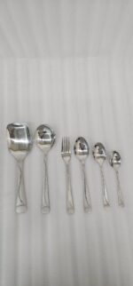 Overhead view of a 37-piece stainless steel cutlery set, including table spoons, forks, knives, and serving utensils arranged on a wooden table, as depicted in 7.jpg.